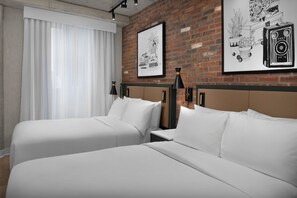 Ett hotellrum med två sängar, en tegelvägg och två inramade tavlor.