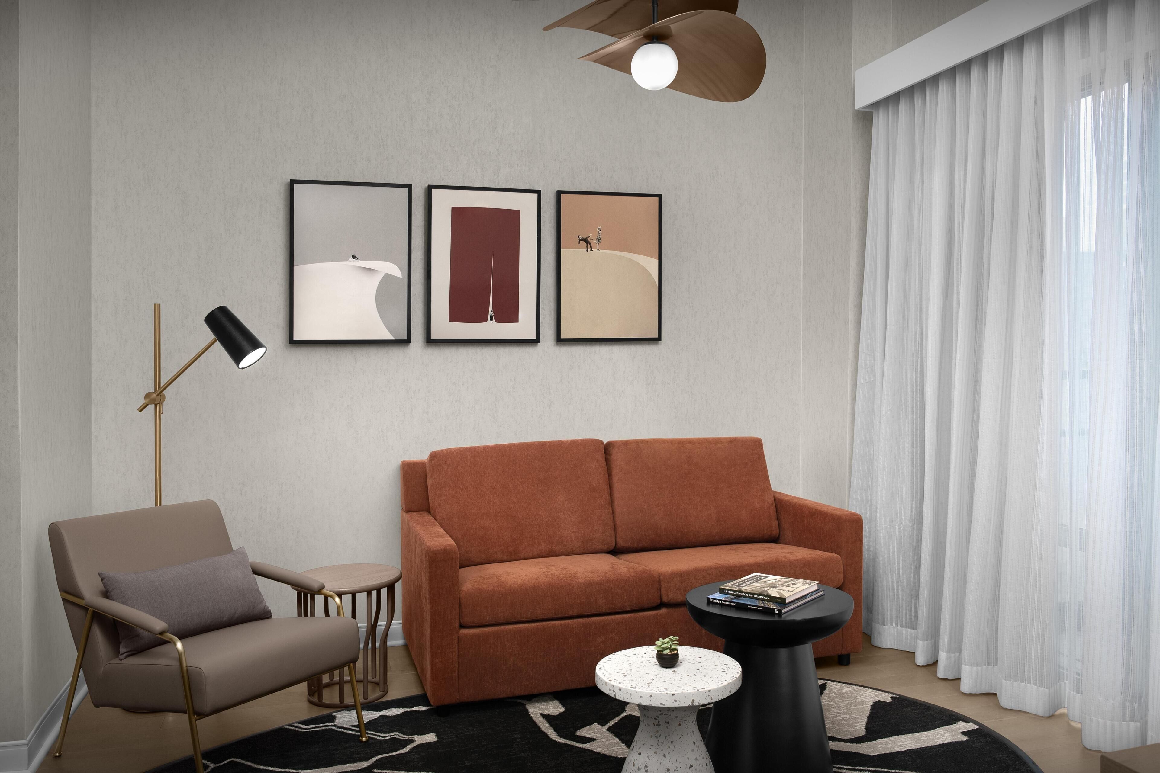 A modern living room with a sofa, armchair, and a coffee table with books.