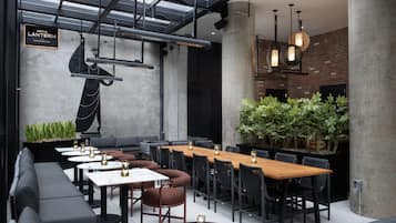 An indoor dining area with a long wooden table, multiple chairs, and a black sofa.