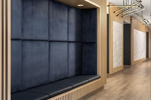 A modern interior with a dark blue cushioned bench, wooden paneling, and a patterned wall.