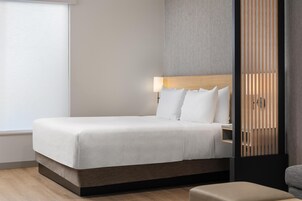 A modern hotel room with a large bed, a bedside table, and a nightstand.