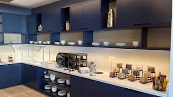 Una cocina moderna con armarios azul oscuro, encimeras blancas y diversos electrodomésticos y utensilios de cocina.
