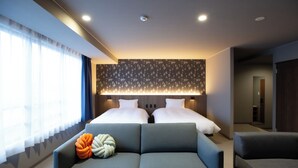 A modern hotel room with two beds, a sofa, and a large window with sheer curtains.