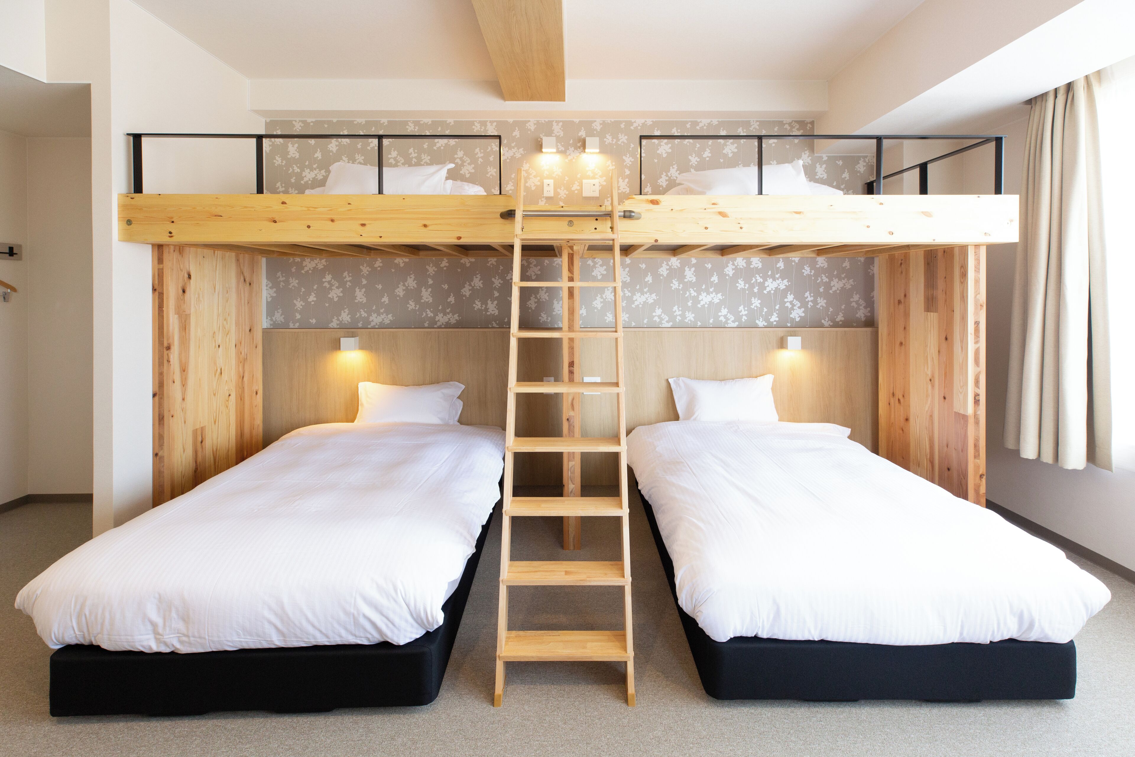A room with two bunk beds, a wooden ladder, and a light fixture between the beds.