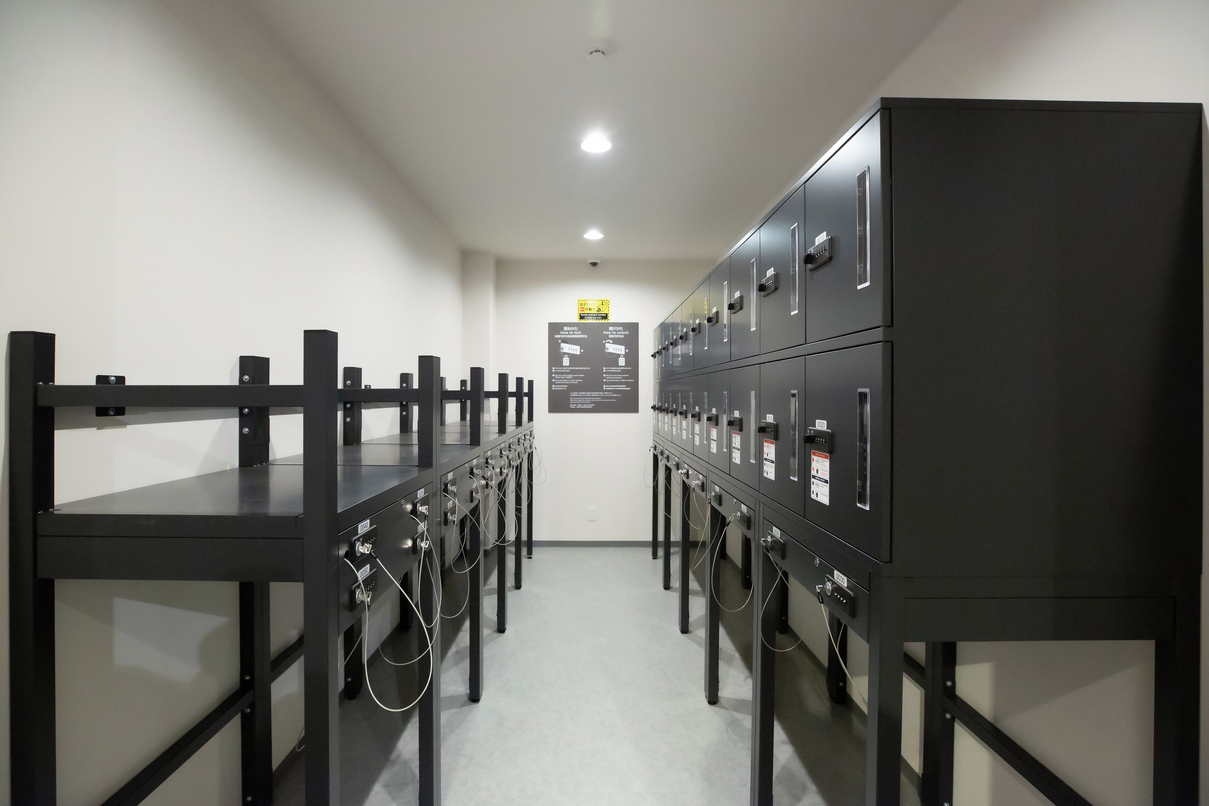 Un bagno moderno e pulito, con una fila di armadietti, uno specchio e un cartello appeso al muro.