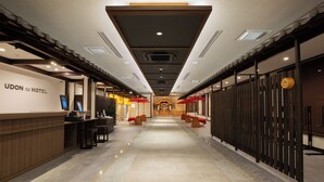 A hotel reception area with a modern design, featuring a reception desk, seating area, and a view towards the hotel's interior.