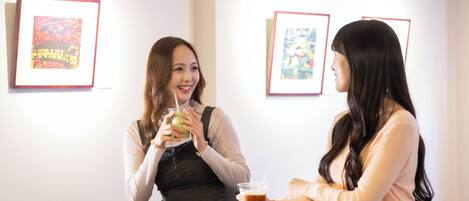 Two people sitting at a table in a room with framed artwork on the walls.
