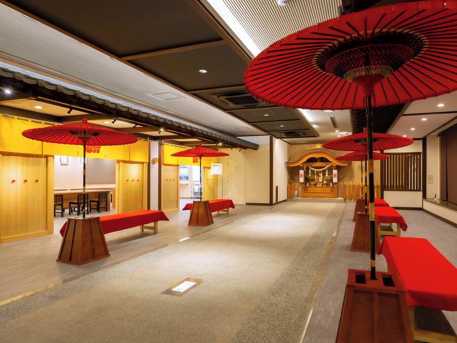 A hotel lobby with red umbrellas, wooden benches, and a reception area.