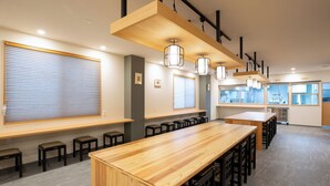 A modern meeting room with a long wooden table, black chairs, and pendant lighting.