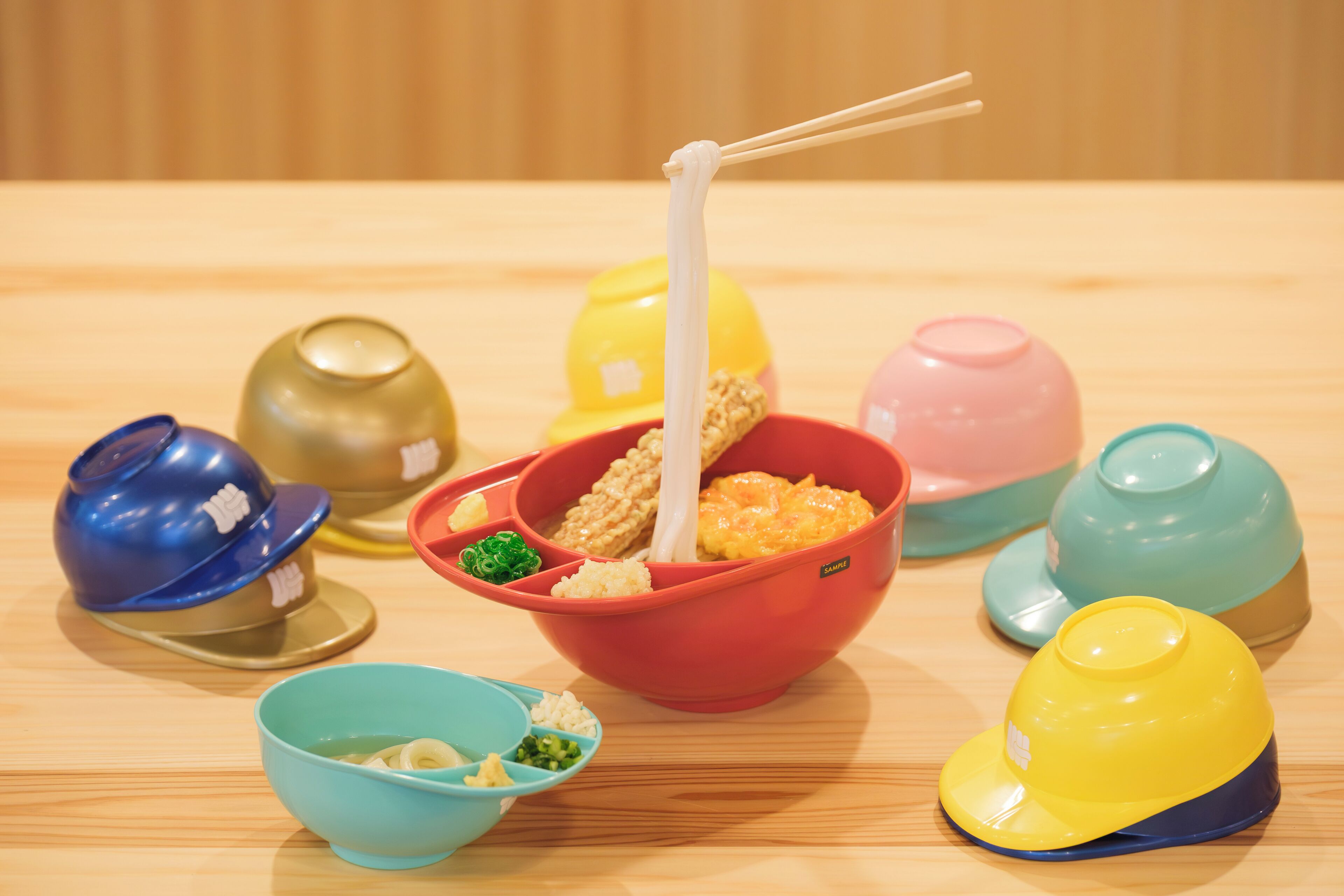 A table with various food items and colorful bowls, some with lids.
