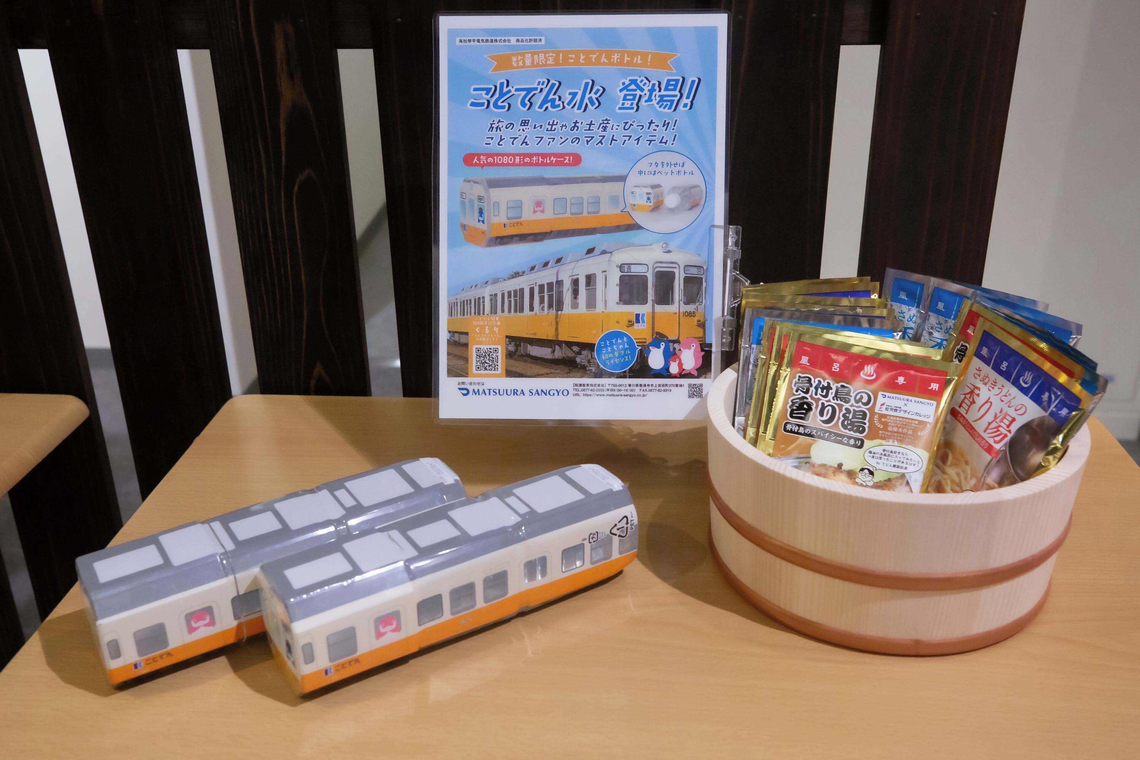 A table with a model train set and a wooden container holding various packaged items.