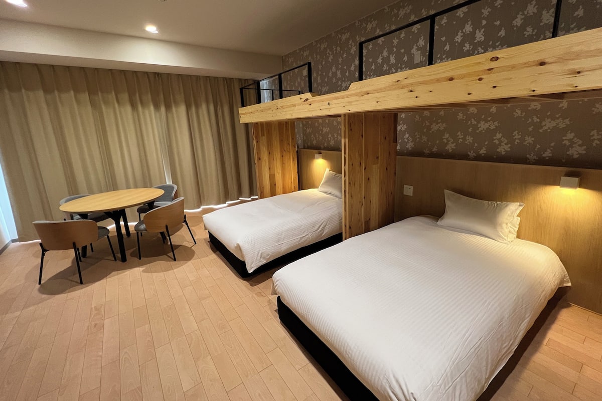 Ein Hotelzimmer mit zwei Betten, einem kleinen Tisch und Stühlen.
