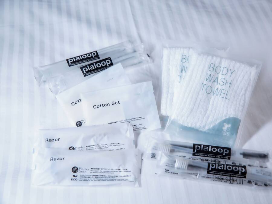 A collection of toiletries including razors, a cotton set, a body wash towel, and a toothbrush, all packaged in plastic.