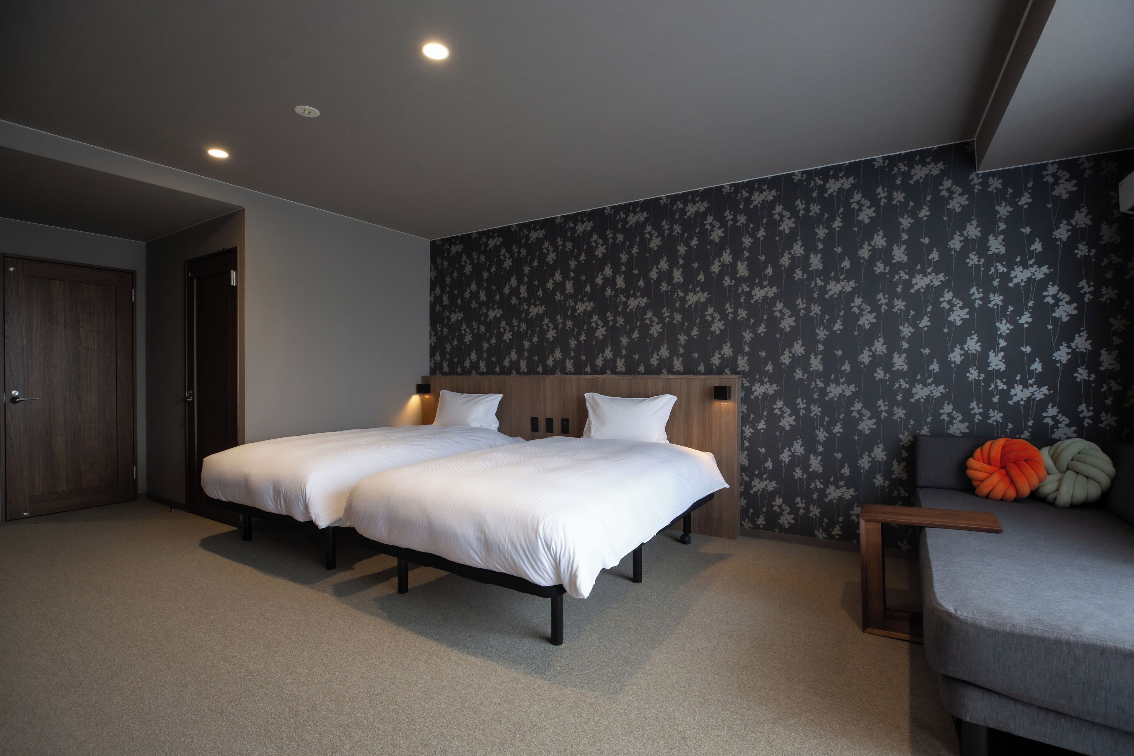 A double bed with a wooden headboard, a bedside table, and a chair with a cushion.
