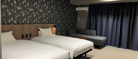 Une chambre d’hôtel avec deux lits, un canapé, un miroir et une fenêtre avec des rideaux.