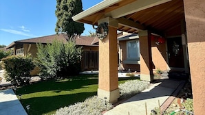 A residential house with a covered porch, a well-maintained lawn, and a tall tree. - Garden vibes - 3BR Home near Downtown (San Jose)