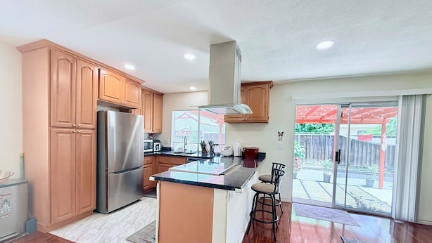 A modern kitchen with wooden cabinets, stainless steel appliances, and a large island. - Garden vibes - 3BR Home near Downtown (San Jose)