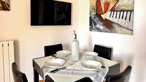 A dining area with a table set for four, a vase with a flower, and two paintings on the walls. - To complete (Bergamo)