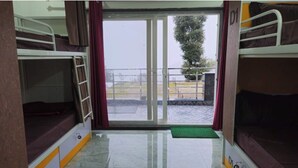 Un dormitorio con literas, una puerta corrediza al balcón y un tapete verde en el suelo.