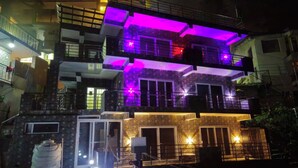 Un edificio de varios pisos con balcones y una entrada protegida por una reja.