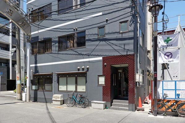 A building with a grey facade, a red brick entrance, and a bicycle parked outside.