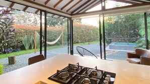 A modern kitchen with a gas stove, a dining table, and a ceiling fan. - Lembos Cabin with Jacuzzi and sky view (Pereira)