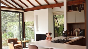 A modern kitchen with a large island, wooden beams, and a view of greenery outside. - Lembos Cabin with Jacuzzi and sky view (Pereira)