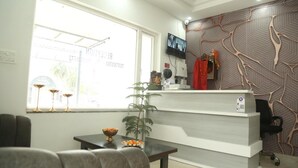 Un'area di accoglienza con una scrivania moderna, una televisione e un muro decorato.