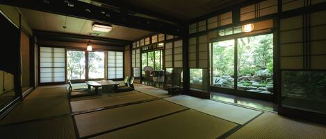 A traditional Japanese room with tatami flooring, sliding doors, and a view of a garden.