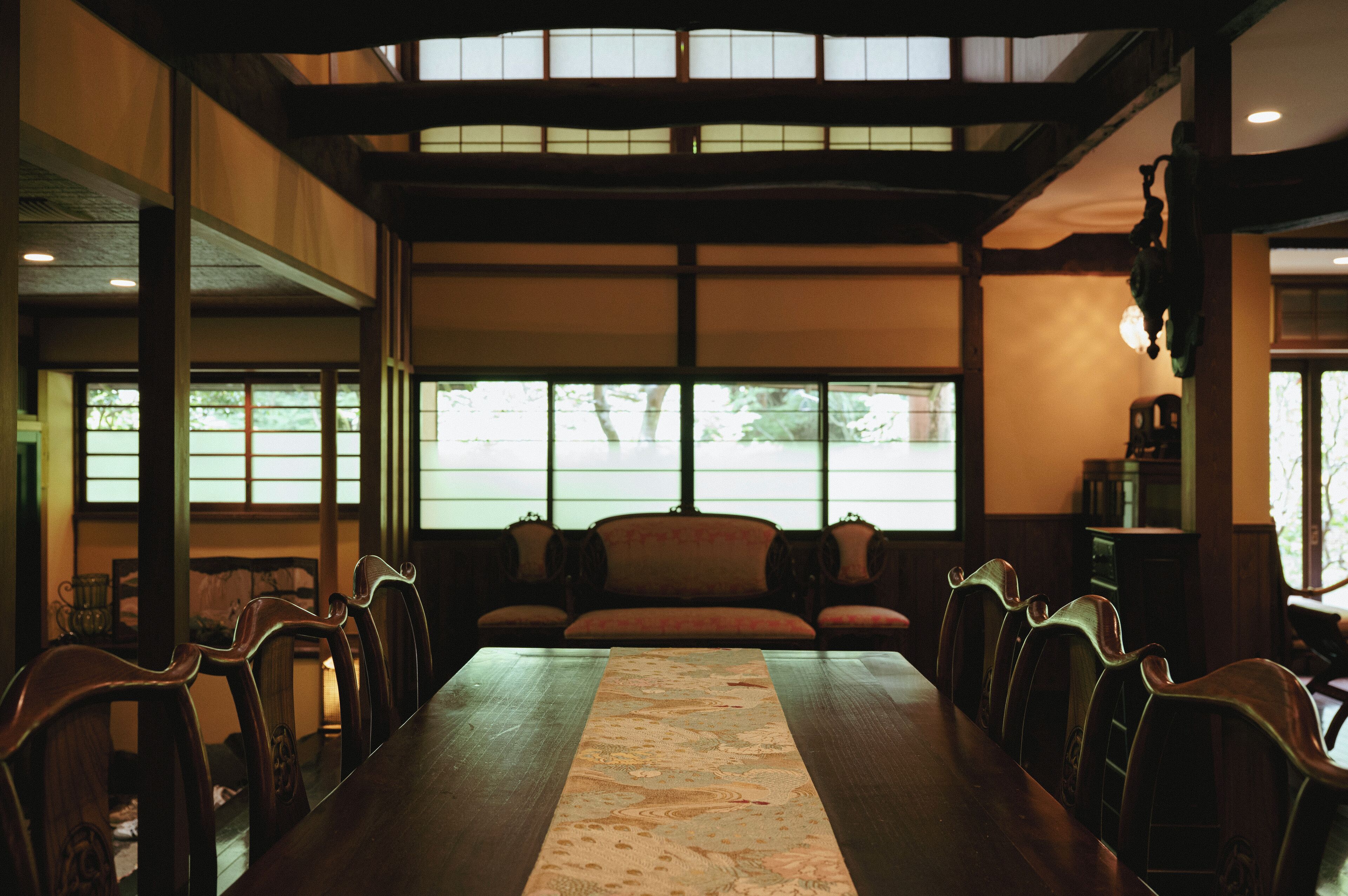 A traditional Japanese-style room with tatami mat flooring, wooden furniture, and large windows allowing natural light.