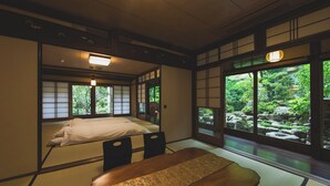 Une pièce de style japonais traditionnel, avec un sol recouvert de tatamis, un lit bas en bois et des portes coulissantes en papier de riz (shoji).