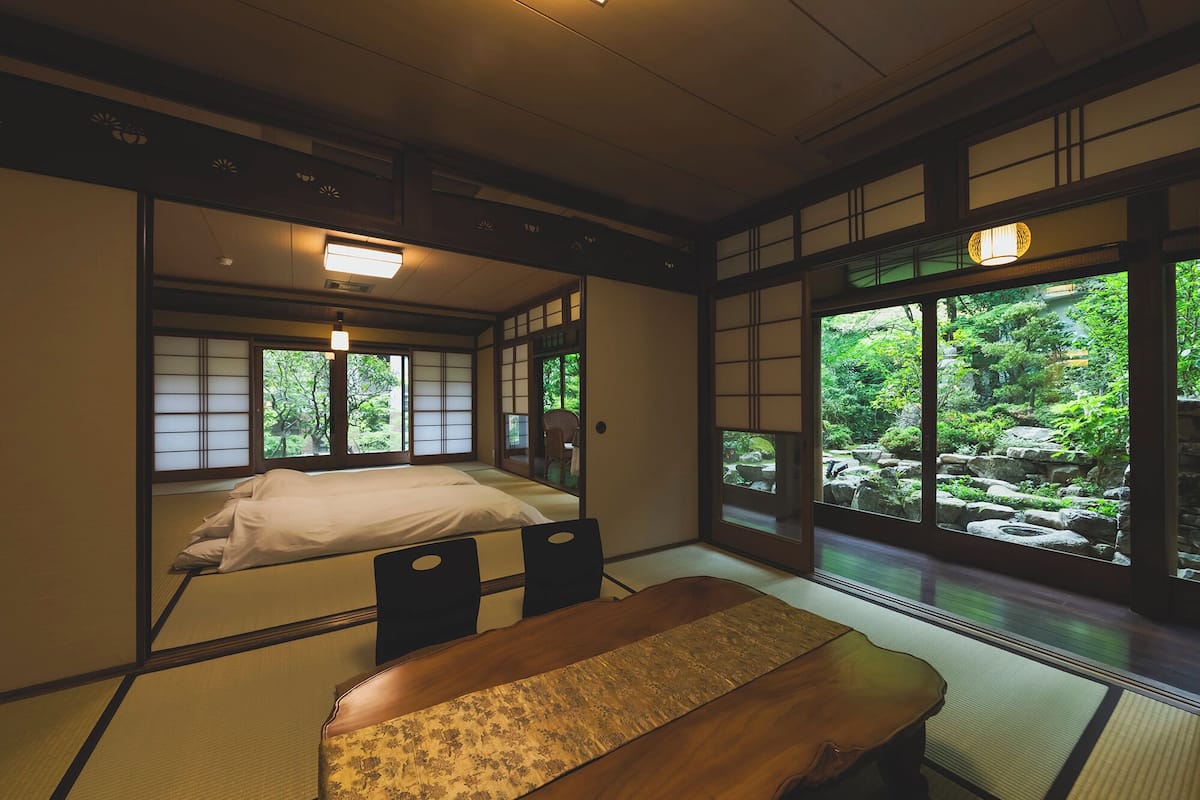A traditional Japanese-style room with tatami flooring, a low wooden bed, and sliding shoji doors.