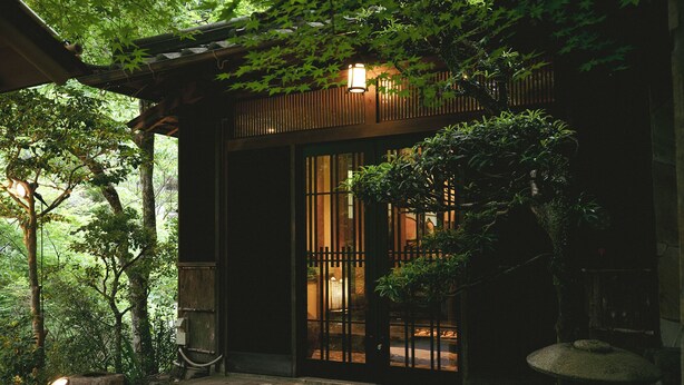 Un bâtiment japonais traditionnel, avec une façade en bois, une entrée carrelée et une lanterne en pierre.