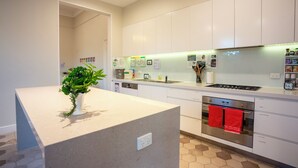 Una cocina moderna con armarios blancos, horno empotrado y encimera con una planta.