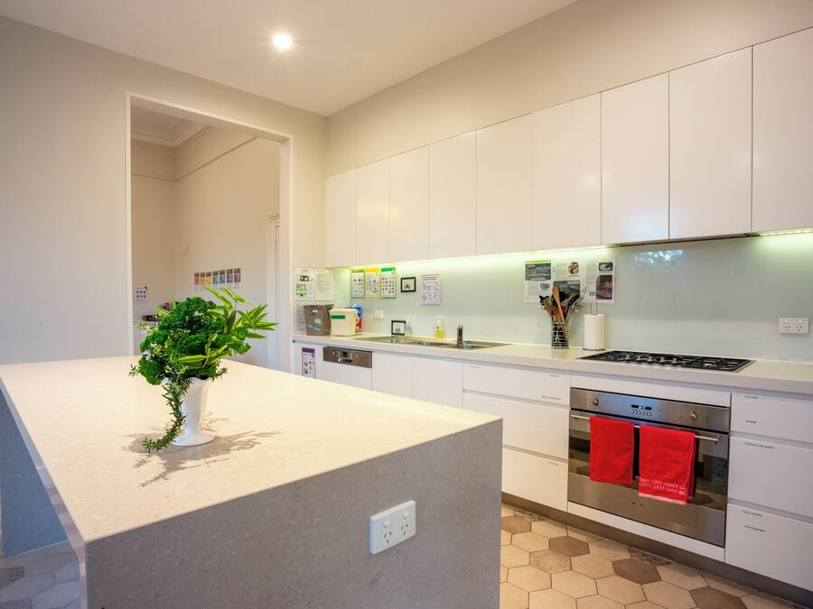 Una cocina moderna con armarios blancos, horno empotrado y encimera con una planta.