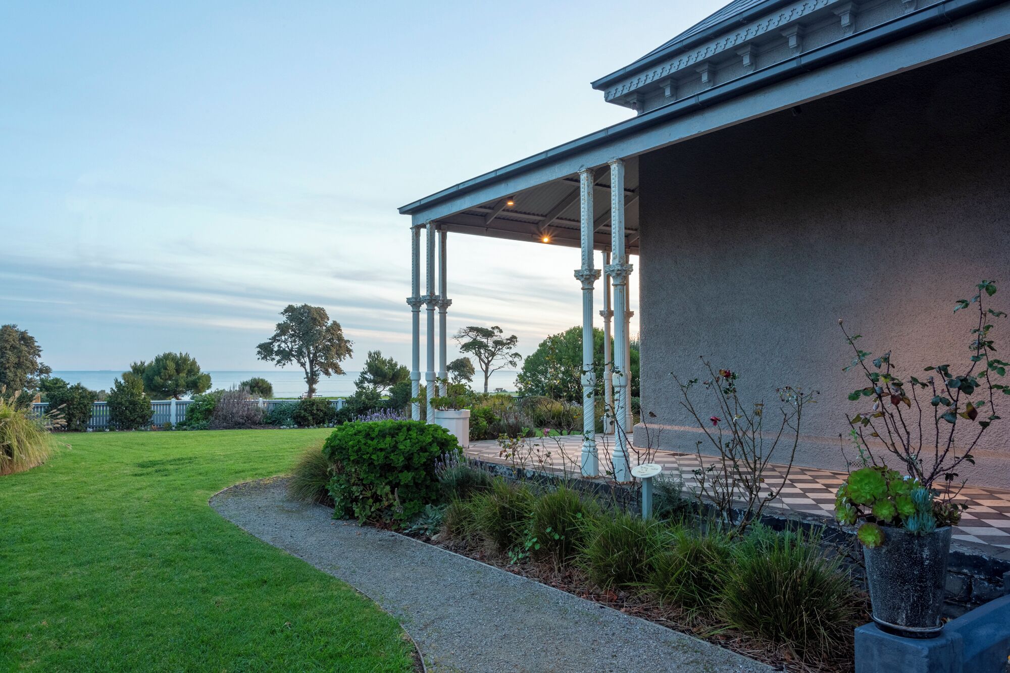 A covered outdoor area with columns, a pathway, and a view of the sea.
