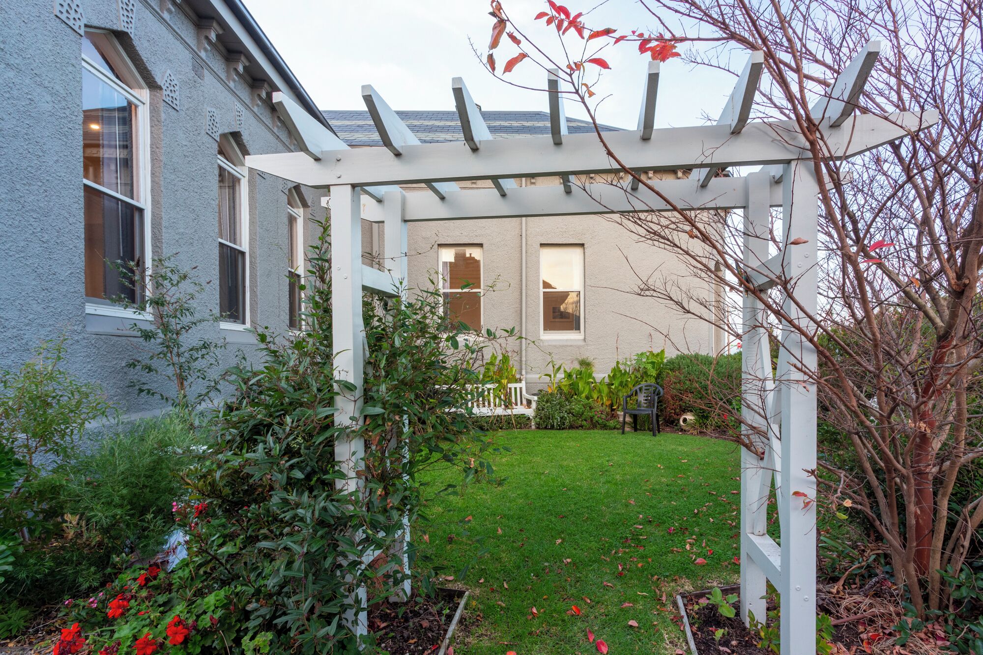 Une maison dotée d’un patio couvert, d’une pelouse et de diverses plantes.