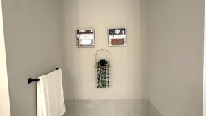 Ein Badezimmer mit einer Badewanne, einem Handtuchhalter und zwei gerahmten Bildern an der Wand.