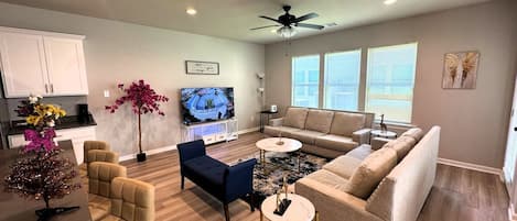 Un salon moderne avec un canapé, des fauteuils, une table basse et un téléviseur.