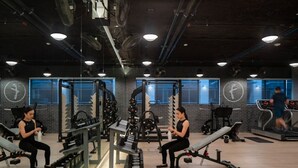 Ein Fitnessstudio mit Kraftgeräten, Laufbändern und einer Spiegelwand.