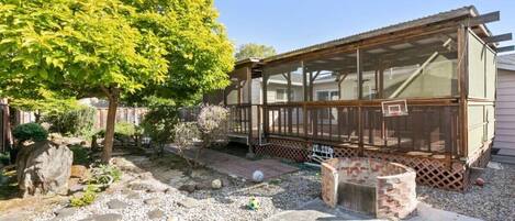 A house with a covered porch, a garden with stepping stones, and a tree.