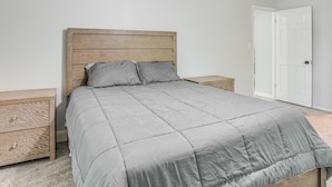 A bedroom with a wooden headboard, a grey bedspread, two bedside tables, and a white door. - Group Getaway w/ Deck & Yard in Lakeland! (Lakeland)
