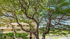 A multi-story building with balconies, surrounded by lush greenery and a curved road. - @ Marbella Lane -coastal Retreat Near Diamond Head (Honolulu)