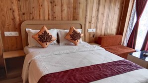A neatly made bed with a white and maroon bedspread, two leaf-patterned pillows, and a wooden headboard. - SUMARU JUNGLE RESORT (Alipurduar)
