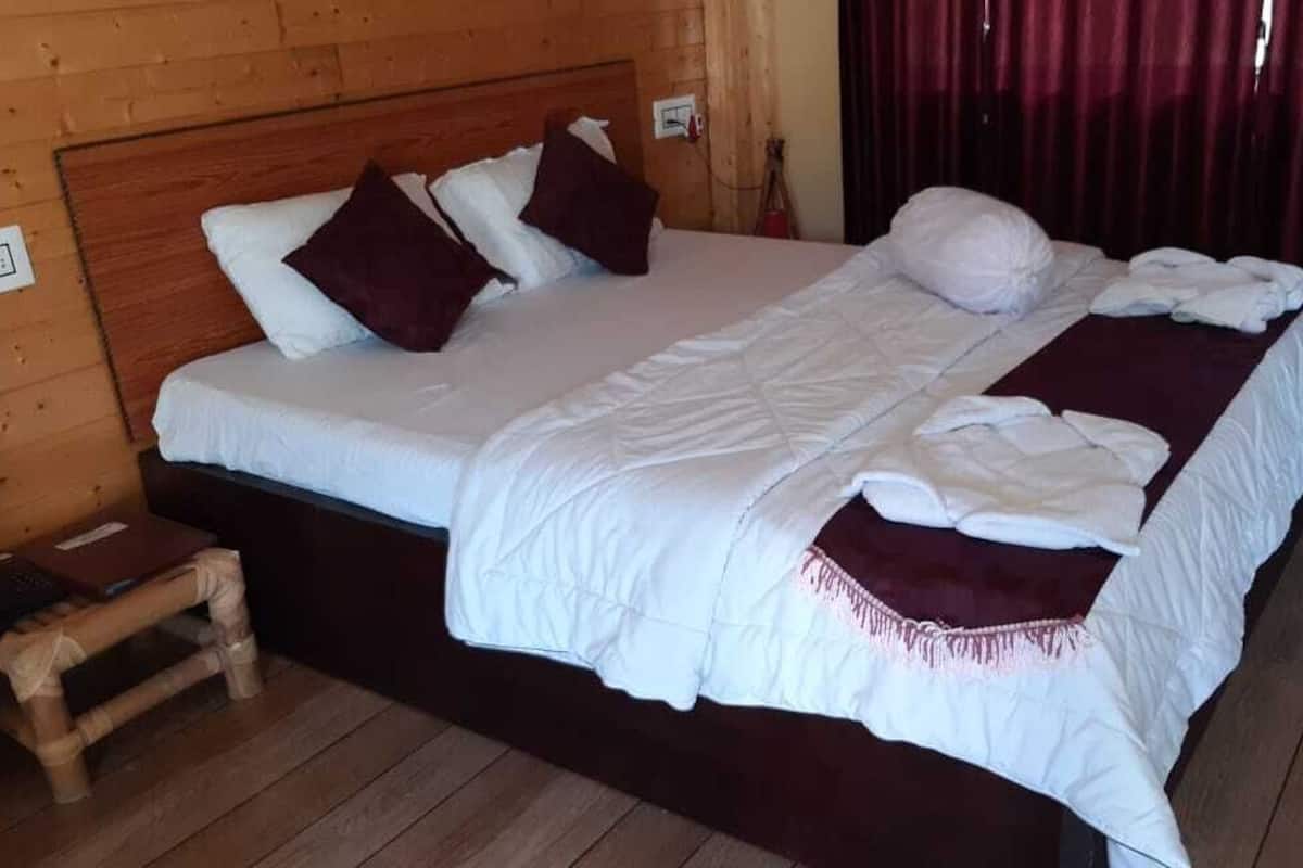 Quarto com painéis de madeira, uma cama grande, uma mesinha de cabeceira de madeira e uma cortina vermelha.