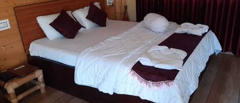 Ein Zimmer mit Holzwandverkleidung, einem großen Bett, einem Nachttisch aus Holz und einem roten Vorhang.