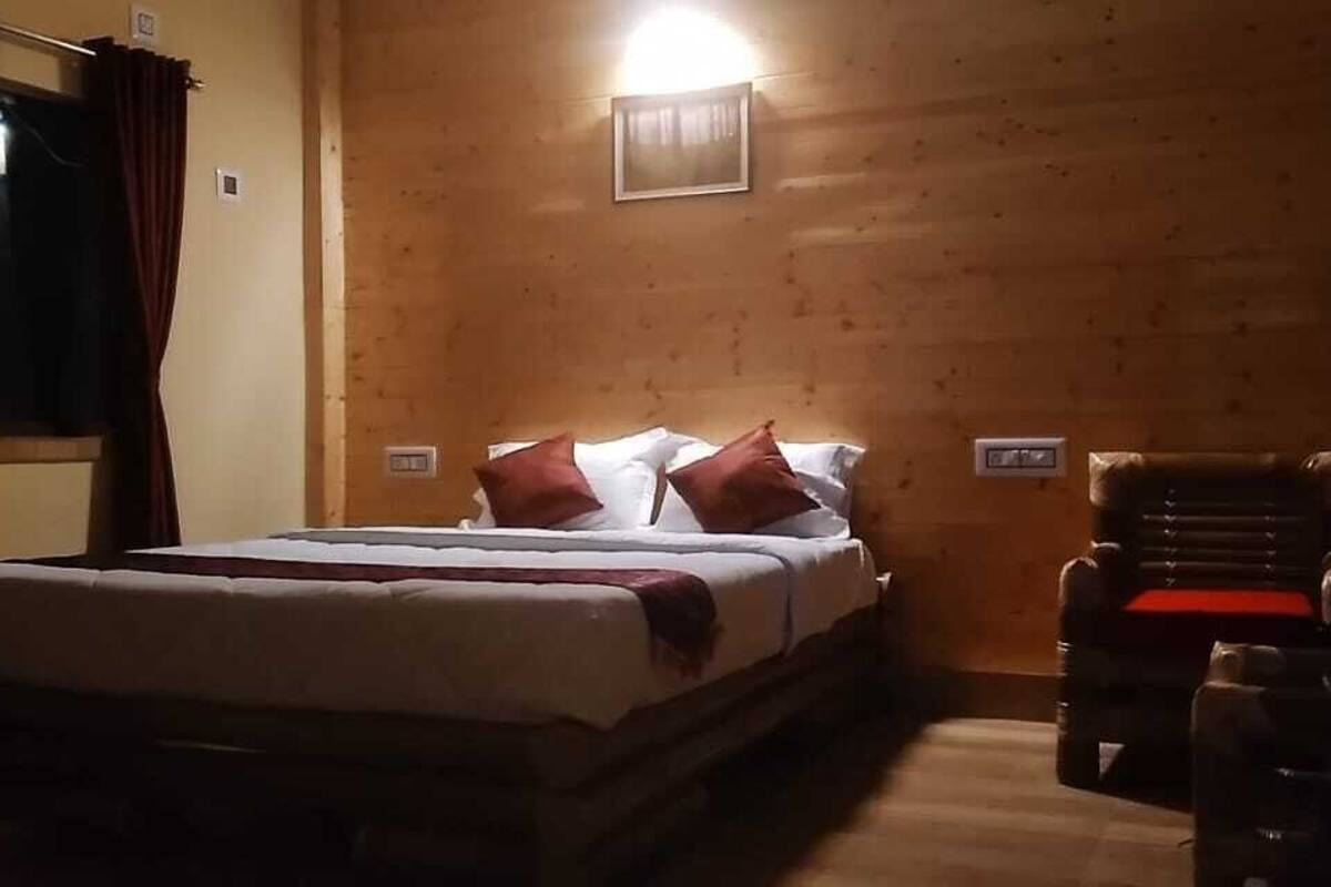 Um quarto com uma cama, uma cadeira e um candeeiro fixado na parede.