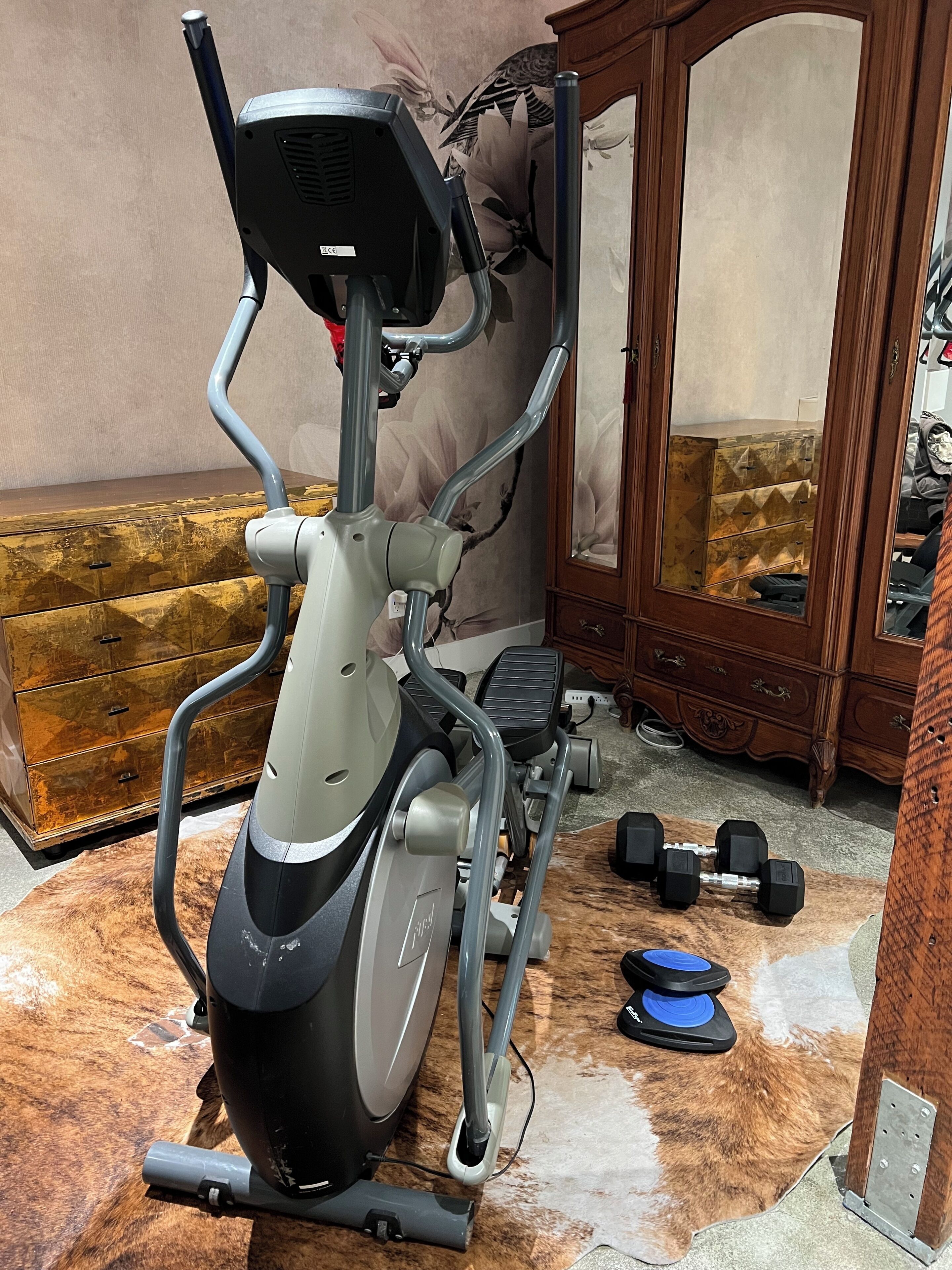 An exercise machine in a room with a wooden cabinet and a mirror.