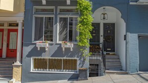 Ein zweistöckiges Haus im viktorianischen Stil mit Erkerfenster, einer Veranda mit Blumenbeet und einer kleinen Treppe zum Eingang.
