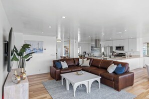 Un salon moderne avec un canapé d’angle, une table basse et un téléviseur à écran plat.